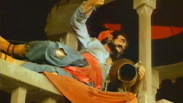 Piraten-animatronic ligt zijwaarts op de reling van een piratenschip en houdt een kelk in zijn hand.